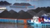 Kapal berlayar di dekat tongkang yang terisi penuh batu bara di sungai Mahakam di Samarinda, Kalimantan Timur, 19 Desember 2022. (AP/Dita Alangkara)