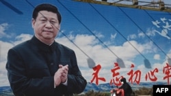 资料照:一名男子骑着电动车路过北京街头的一幅宣传画。(2023年2月28日)