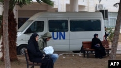 2024年1月28日,流离失所的巴勒斯坦人坐在长椅上,在加沙地带南部拉法的联合国援助机构的诊所外等候。(法新社照片)