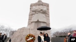 2024年1月15日,马丁·路德·金三世在女儿约兰达·蕾妮·金和妻子安德里亚·沃特斯·金的陪同下,在华盛顿马丁·路德·金纪念园举行的年度马丁·路德·金花圈仪式上合影留念。(美联社照片)