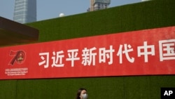 一名女子从北京街头张贴的一条宣传习近平新时代的标语下走过。(2019年9月27日)