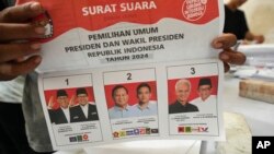 Seorang pekerja memegang surat suara untuk pemilihan presiden 14 Februari yang menunjukkan foto ketiga paslon, saat persiapan distribusi logistik pemilu di Tangerang, Indonesia, 10 Januari 2024. (Foto: Tatan Syuflana/AP Photo)