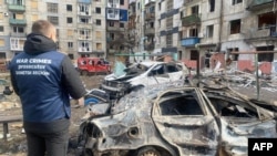 乌克兰顿涅茨克地区一栋被俄罗斯导弹摧毁的居民楼房和附近受损的汽车。(2024年3月10日)