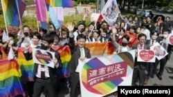 日本一家法院裁定,不允许同性婚姻是违宪后,日本民众挥舞彩虹旗帜和标语庆祝。(2023年5月30日)