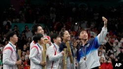 在乒乓球混双比赛中,中国队夺冠,朝鲜队获得银牌,韩国队获得铜牌,韩国选手林钟勋在颁奖仪式后邀请中国和朝鲜选手自拍合影。(美聯社:2024年7月30日)