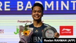 Anthony Sinisuka Ginting berpose di podium setelah mengalahkan Anders Antonsen dari Denmark pada pertandingan final tunggal putra turnamen bulutangkis Singapore Open pada 11 Juni 2023. (Foto: AFP/Roslan RAHMAN)