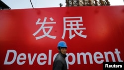 资料照：一名工人走过北京一处建筑工地的宣传标语。（2014年12月12日）