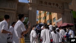 图为2023年6月7日,中国的应届高中毕业生们在一个中学外排长队参加每年一次的“全国高校统一考试”,俗称“高考”,一名警察站在一旁注视着排队的学生。今年全中国有超过120万的高中毕业生参加高考。