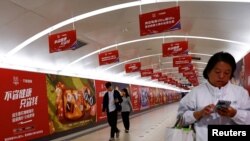 资料照：北京地铁乘客走过阿里巴巴为11月11日光棍节大促销所作广告的通道。（2023年10月26日）