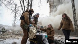 Para pekerja medis merawat seorang warga setempat yang terluka di lokasi bangunan tempat tinggal yang rusak berat akibat serangan rudal Rusia, di Kharkiv, Ukraina Selasa (23/1).