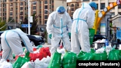 西藏拉萨街头身穿防护服的大白为被封在家中的居民们整理食品袋。(2022年9月29日)