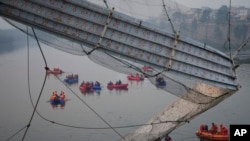 印度古吉拉特邦莫比镇的拉索桥崩塌后,救援人员乘舟在河上搜寻。(2022年10月31日)