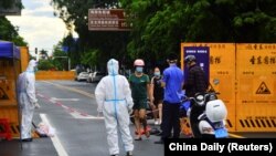 海南省三亚一个居民小区被封后快递员在小区门口递送食物。(2022年8月8日)