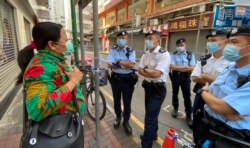 住在佐敦封鎖區內的尼泊爾籍居民Rai在社區封鎖前離家上班,她下班返家才知道當局已經實施封區禁足強制檢測,她向在場駐守的警員查詢如何返回封鎖區內。(美國之音 湯惠芸拍攝)