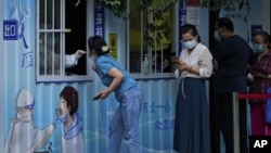 (2022年8月29日)北京居民在一条街道上接受日常新冠病毒咽拭子检测。(美联社照片)