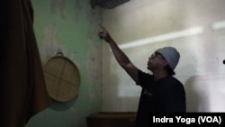 Heru Sutanto menunjuk dinding rumahnya yang mengalami keretakan cukup parah sehingga kamar tidur tersebut tidak lagi digunakan karena khawatir akan membahayakan anak dan istrinya. (VOA /Indra Yoga)