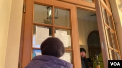 一名妇女正在阅读一份需要帮助解决紧急需求的志愿者名单(美国之音德特默拍摄)。