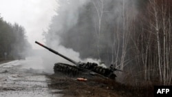 在卢甘斯克地区的路边,被乌军摧毁的一辆俄军坦克冒着浓烟。(2022年2月26日)