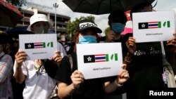 泰国抗议者们举着带有奶茶联盟标签的手牌。(2020年8月16日)