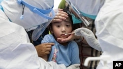 在武汉大规模检测 COVID-19 时，一名儿童正要做咽拭子检测。（2021年8月3日） 