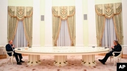 资料照片:俄罗斯总统普京在克里姆林宫隔着一张长桌与联合国秘书长古特雷斯会谈。(2022年4月26日)