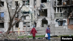 乌克兰马里乌波尔的居民走过被战火摧毁的居民楼宇(2022年4月22日)