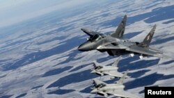 资料照:波兰空军的米格-29战机(上)与意大利空军的台风战机参加北约空中警卫行动在波罗的海上空巡逻。(2015年2月10日)