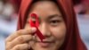 FILE - Seorang pelajar Indonesia memegang pita merah sebagai bagian dari acara kesadaran pada peringatan Hari AIDS Sedunia di Medan, provinsi Sumatera Utara, 2 Desember 2018. -(Albert Ivan Damanik/AFP)