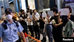 香港市民手持白纸和花束悼念新疆火灾死难者,支持中国内地的抗议活动。香港警察前去查看他们的身份证。(2022年11月28日)