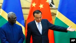 资料照:2019年10月9日日,所罗门群岛总理索加瓦雷(左)和中国国务院总理李克强出席在北京人民大会堂举行的签字仪式。