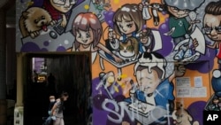 2022年3月22日,一名妇女和小孩戴着口罩走在香港的一条街道上。(美联社)