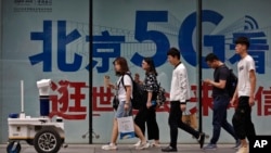 人们在北京街头一个购物区的5G网络广告前走过。(2019年5月15日)