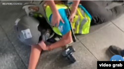 印尼女记者英达(Veby Indah)被橡皮子弹打中右眼倒地瞬间。(美国之音电视画面视频截图)