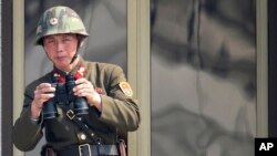 2013年4月4日,在南北双方边界的板门店非军事区,一名朝鲜士兵在观看对方韩国的情况。