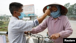 越南一名卫生工作者正在检测一名农民的体温(2020年2月12日)。