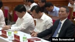 Ông Nguyễn Xuân Anh (giữa) cúi đầu nhìn vào màn hình điện thoại khi Trưởng ban Tổ chức Trung ương Phạm Minh Chính công bố quyết định bổ nhiệm ông Trương Quang Nghĩa (phải).