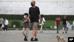 台北市民戴着口罩遛狗散步。(2022年4月27日)