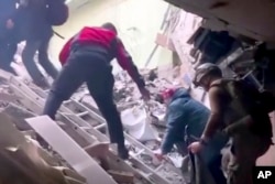 视频截图显示,在乌克兰马里乌波尔一些平民正在爬出被炸成废墟的亚速钢铁厂。(2022年5月1日)