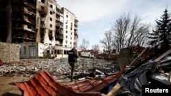 俄军战争罪调查小组一名成员站在基辅地区一座被俄军炮火摧毁的大楼前打电话。(2022年4月7日)