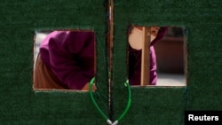 一位上海居民从被锁住的住宅楼门里向外张望。(2022年5月3日)