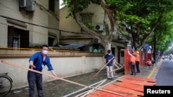 上海工人在拆除封闭街道的围栏。(2022年5月30日)