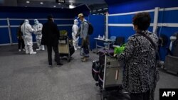 资料照:抵达上海浦东国际机场的旅客等候将要运载他们去隔离酒店的车辆。(2022年1月18日)