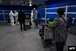 资料照：抵达上海浦东国际机场的乘客等候将要运载他们去隔离酒店的车辆。（2022年1月18日）