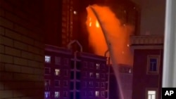 视频截图显示,乌鲁木齐消防人员向发生大火的住宅楼喷水灭火。