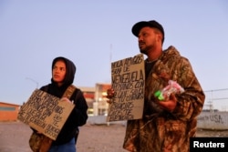 2023年1月7日,来自委内瑞拉的移民在美墨边境举着标牌寻求救助。