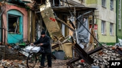 在顿涅茨克地区的巴赫穆特，一位当地居民推着自行车走过废墟和阻挡坦克的障碍物。(2023年1月6日)