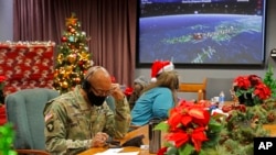 资料照:美国国防部发布的照片显示,在科罗拉多州彼得森空军基地的北美空防司令部里,基地官兵与志愿者在电话和电邮上回答来自世界各地儿童有关圣诞老人行踪的问询。(2021年12月24日)