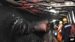 在新华社发布的这张照片中，中国东部安徽省宿州市前营子煤矿的矿工们2021年10月20日在机器旁劳动。