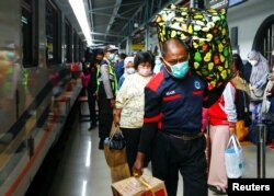 Penumpang membawa barang bawaan mereka saat berjalan di stasiun kereta api untuk mudik menjelang perayaan Idul Fitri, di tengah pandemi COVID-19, di Jakarta, 5 Mei 2021. (REUTERS/Ajeng Dinar Ulfiana)