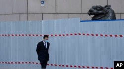 上海一家商场围栏外走过一名戴着口罩的工作人员。(2022年4月20日)